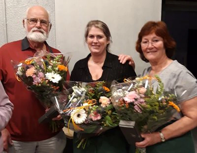 Drie vrijwilligers van het Groene Eikdiner met bloemen bij hun huldiging in 2024